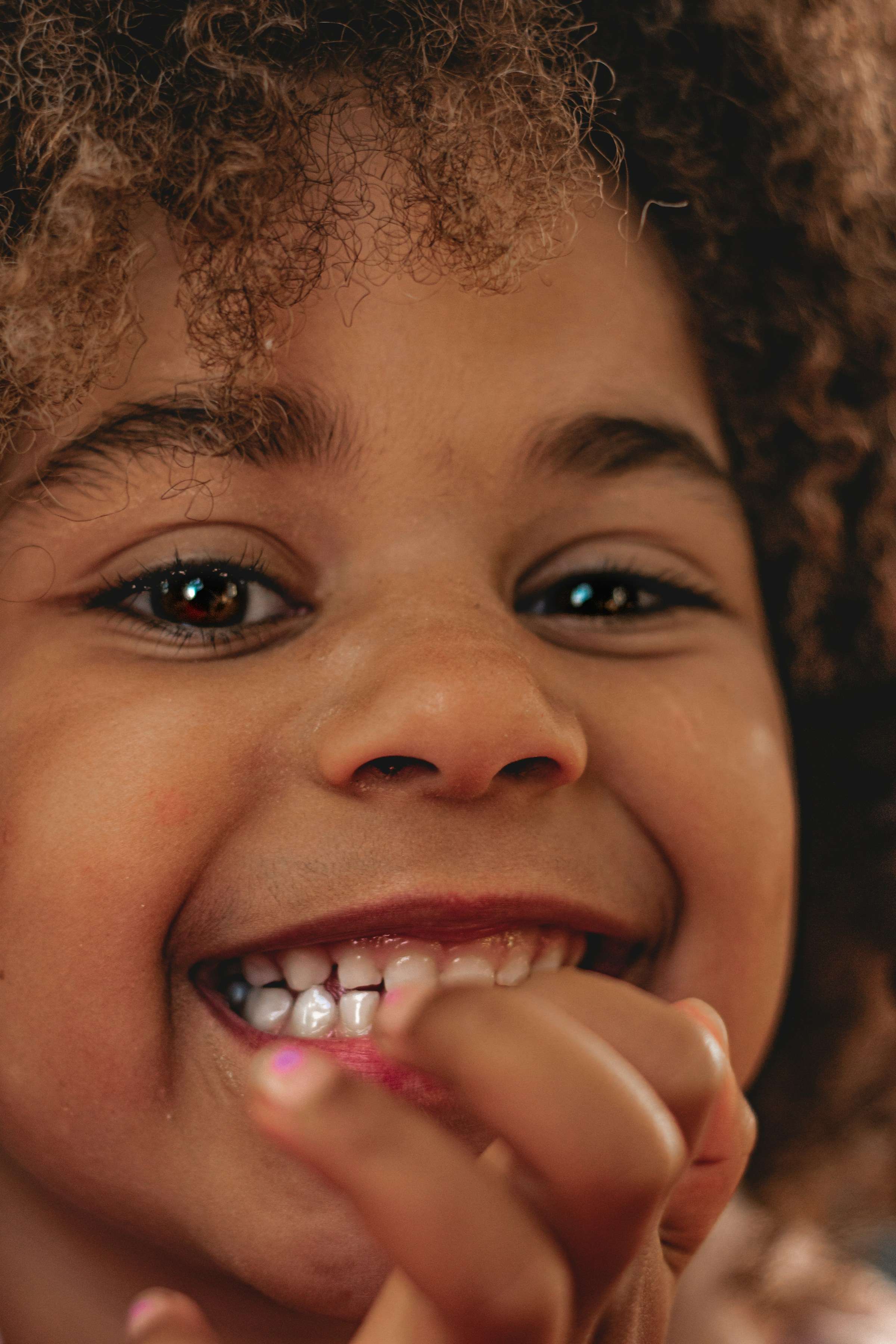 A smiling child brushing her teeth