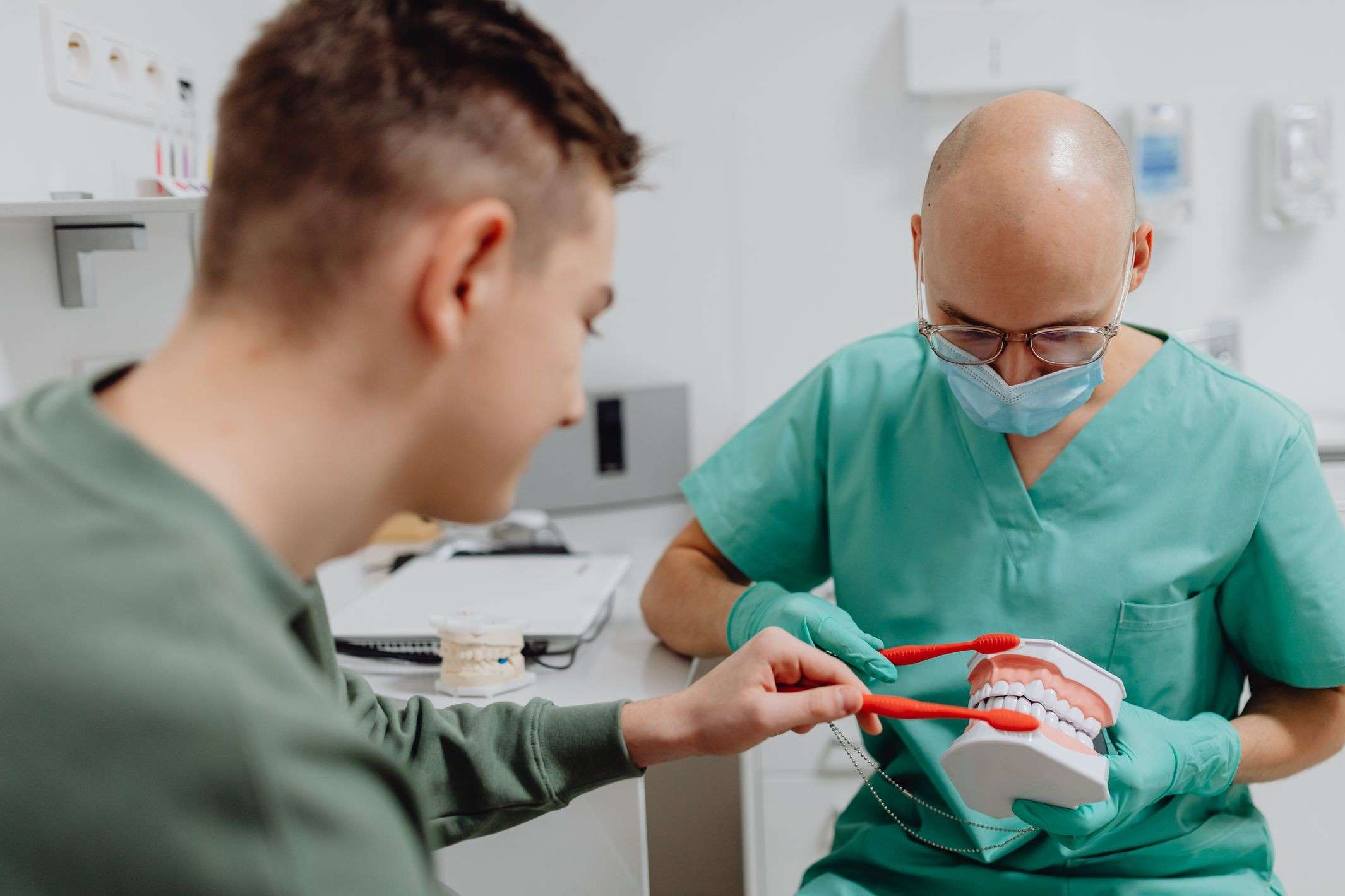 Dr. Holloway shows a teenage patient how to brush on a model
